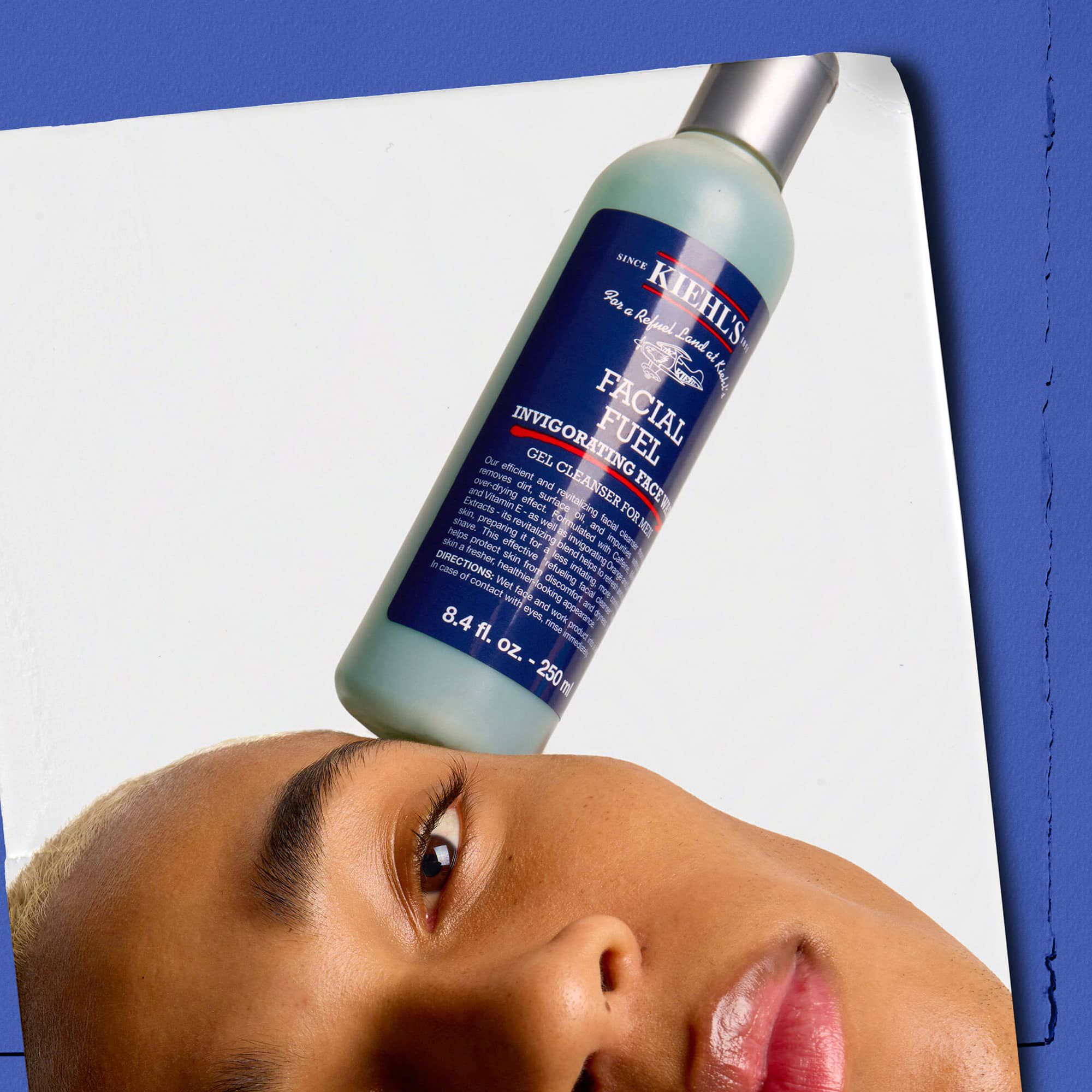 Mannequin avec un flacon du Nettoyant Visage Energisant Facial Fuel de Kiehl's en equilibre sur son visage