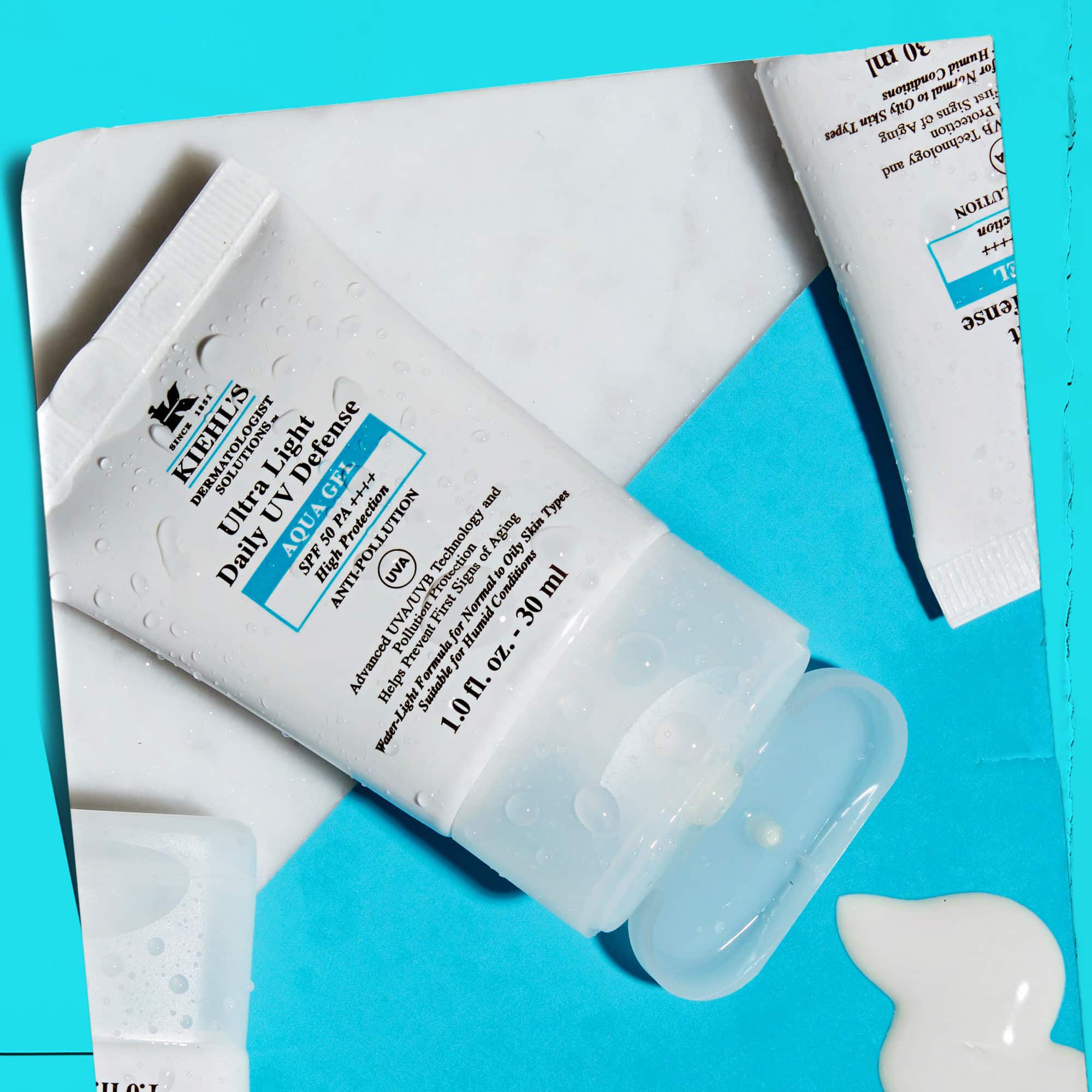 Une vue a plat de plusieurs tubes d'Ultra Light Daily UV Defense Aqua Gel sur une surface en marbre, illustrant leur attrait lifestyle.