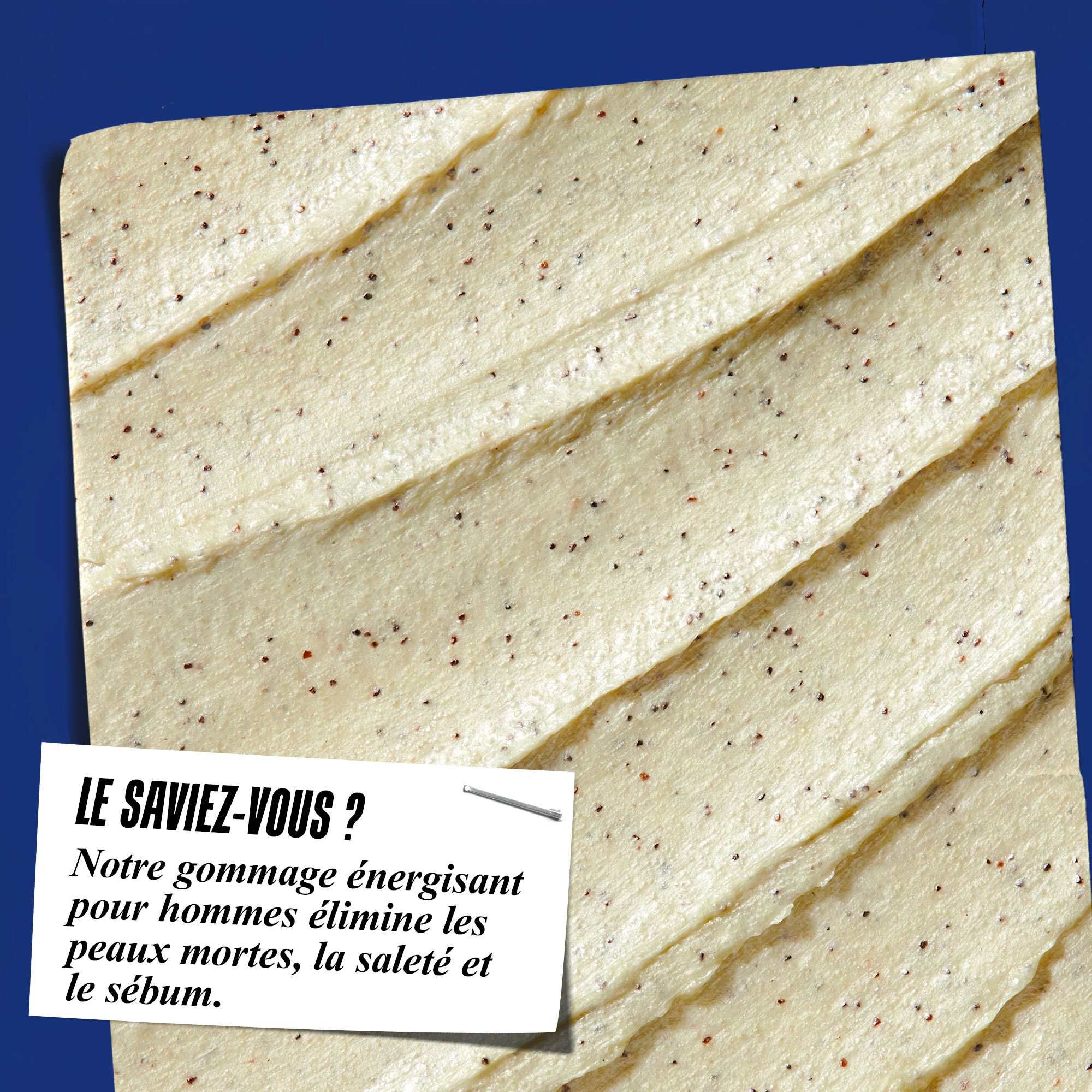 Gros plan sur la texture du gommage Facial Fuel Energizing Scrub. Le texte indique : « Le saviez-vous ? Notre gommage visage energisant pour hommes elimine les peaux mortes, les impuretes et l'exces de sebum. »