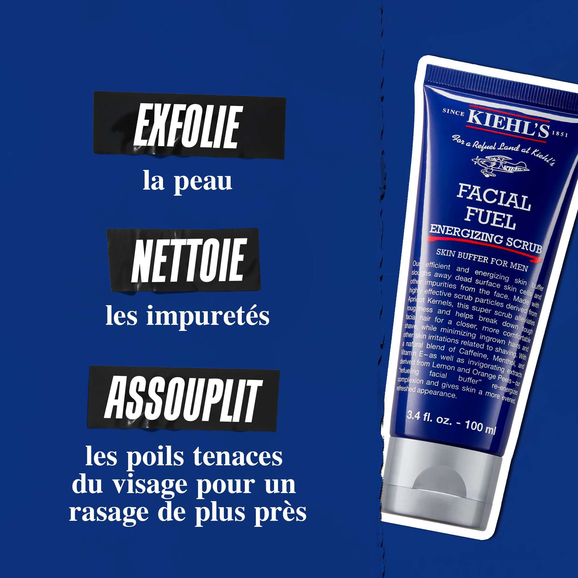 Tube de gommage Facial Fuel Energizing Scrub sur fond bleu fonce. Le texte indique : « Exfolie la peau, elimine les impuretes et adoucit les poils drus pour un rasage de plus pres. »
