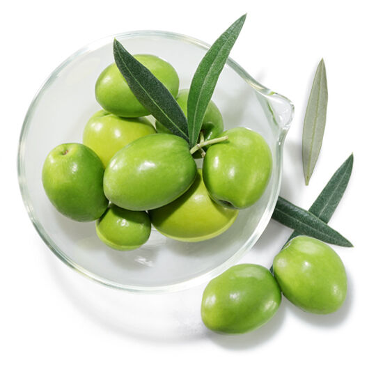 Coupelle en verre avec olives vertes et feuilles, symbolisant le squalane