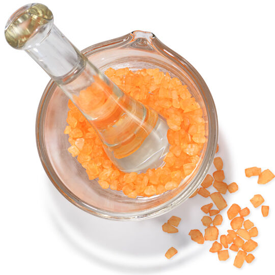 Mortier et pilon en verre avec des cristaux orange, representant de la vitamine C activee