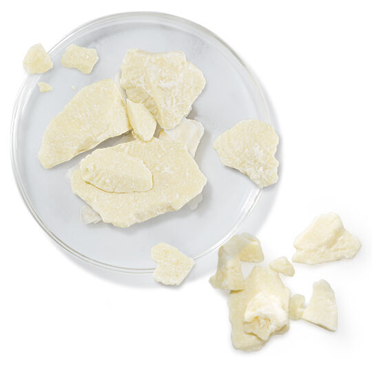 Coupelle en verre avec des morceaux de beurre de cacao, representant un ingredient hydratant.