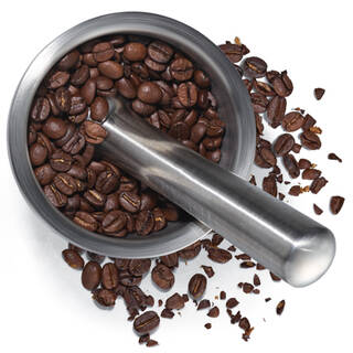 Mortier et pilon en metal avec grains de cafe, representant la cafeine, un ingredient energisant ou exfoliant.