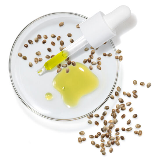 Pipette d'huile vegetale jaune avec des graines sur une coupelle, representant un huile de graines de chanvre