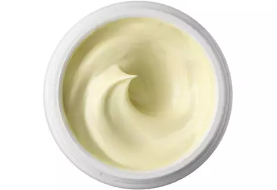 A close-up view of a creamy, pale yellow moisturizer in a circular container, showcasing its smooth, swirled texture.