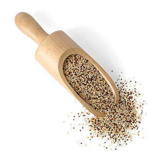 Pelle en bois remplie de graines de quinoa multicolores, representant un ingredient riche en nutriments.