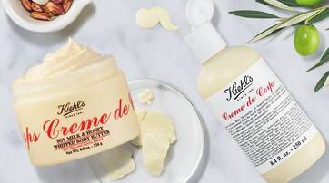 Creme corporelle Kiehl's en pot et flacon, avec une texture cremeuse, posee sur une surface claire avec des ingredients naturels en arriere-plan.