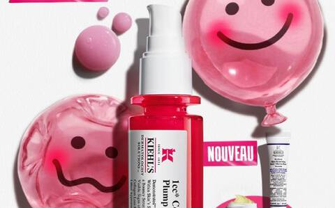 Des produits de soin disposes sur un fond en papier blanc texture. L'element principal est un flacon de serum pour le visage en verre translucide rose vif, dote d'une pompe blanche
