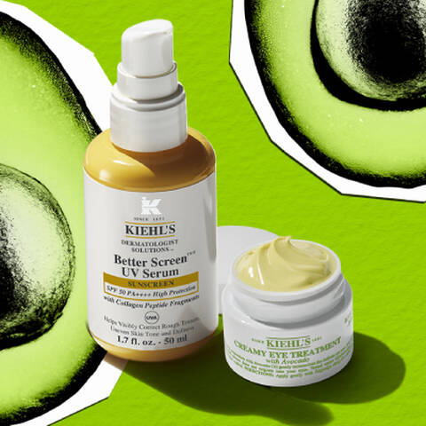 Un pot de soin contour des yeux couvercle ouvert, a cote d'un flacon pompe jaune et blanc, les deux projetant des ombres sur un fond vert avec deux avocats.