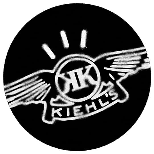 Logo Kiehl’s en style graffiti blanc sur fond noir, avec des ailes et des rayons lumineux.