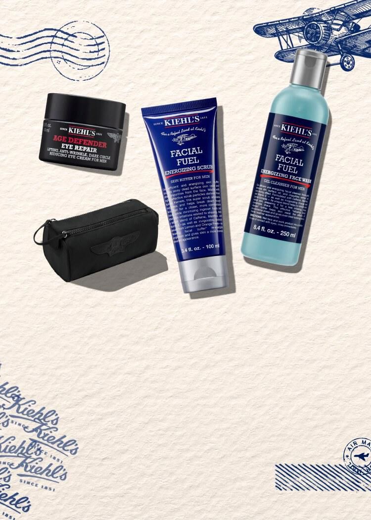 Visuel publicitaire de la gamme homme Kiehl's sur fond creme vintage a motifs aeronautiques bleus. A droite, trois produits cosmetiques sont disposes a cote d'une petite trousse de toilette noire : le gel nettoyant 'Facial Fuel Energizing Face Wash', le gommage 'Facial Fuel Energizing Scrub' et le soin contour des yeux 'Age Defender Eye Repair'.