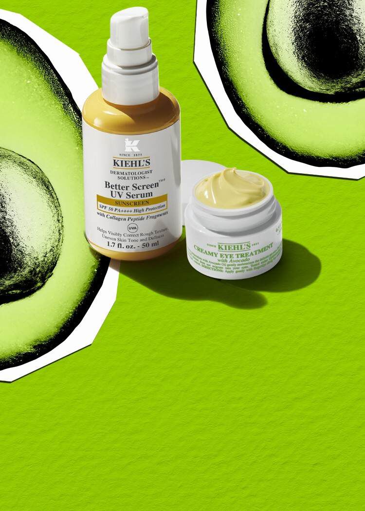 Un pot de soin contour des yeux couvercle ouvert, a cote d'un flacon pompe jaune et blanc, les deux projetant des ombres sur un fond vert avec deux avocats.