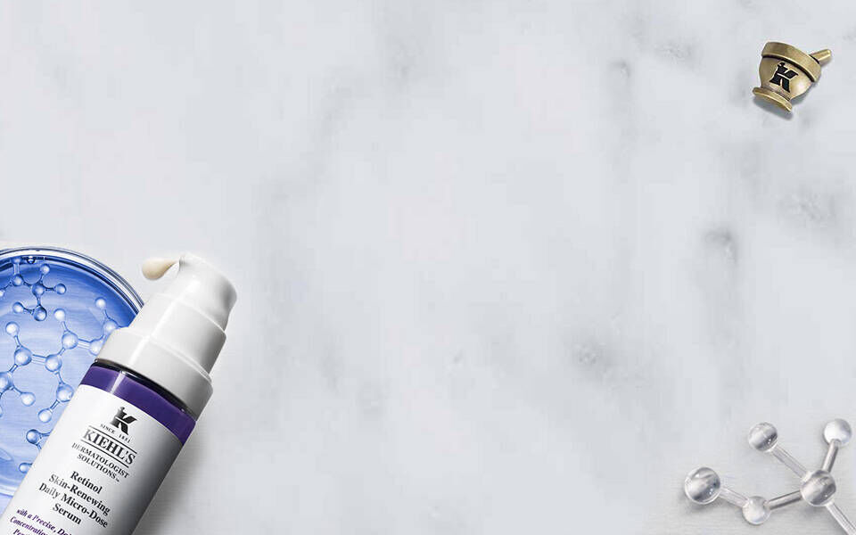 Produits de soins de la peau sur un fond marbre, incluant un flacon de creme et un tube de serum.