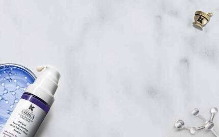 Produits de soins de la peau sur un fond marbre, incluant un flacon de creme et un tube de serum.