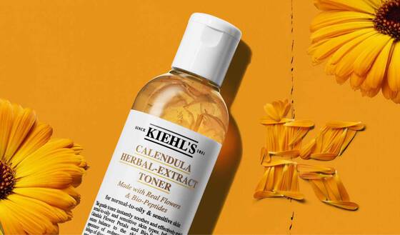 Visuel du Kiehl's Calendula Herbal-Extract Toner, formule avec de vraies fleurs de calendula et des bio-peptides pour les peaux normales a grasses et sensibles, presente sur fond orange dore avec des fleurs et petales de calendula frais.