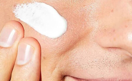 Un gros plan d'un visage avec une creme appliquee sur la joue.