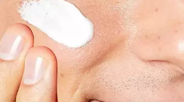 Un gros plan d'un visage avec une creme appliquee sur la joue.