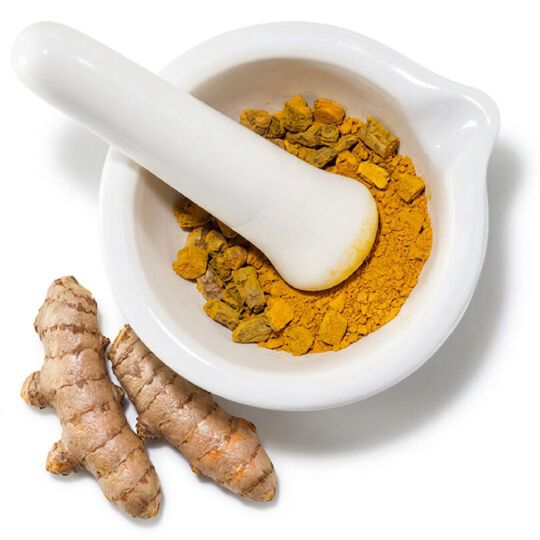 Poudre de curcuma et racines fraiches, illustrant un ingredient aux proprietes antioxydantes.